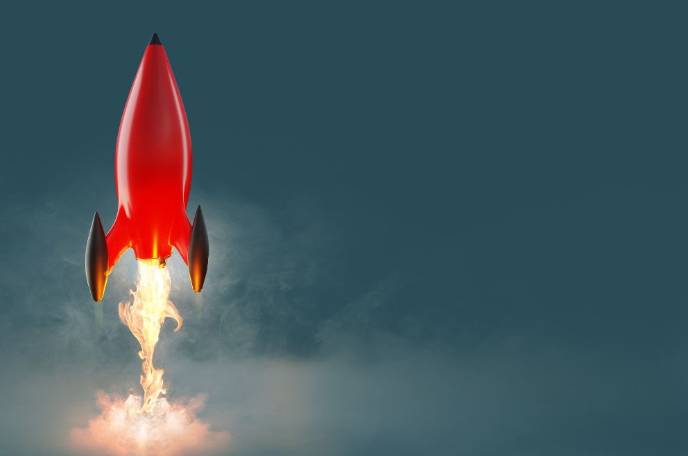 Image of a red rocket starting to take off with a dark blue background.