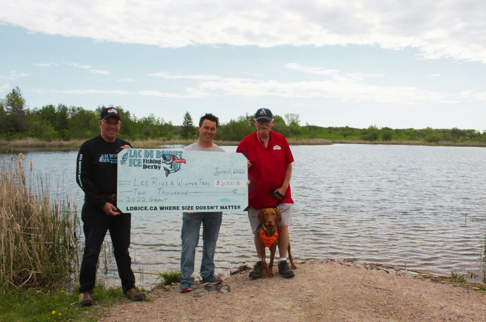 Derby member presents large cheque to two Lee River Winter Trail Members in front of the Lac du Bonnet Wildlife Ponds.