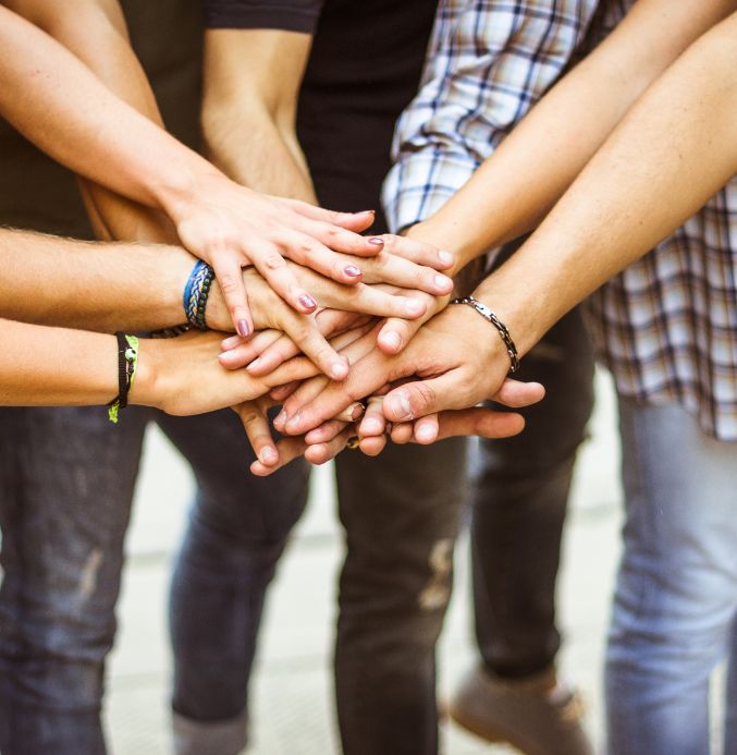 Close up of a group of people stacking hands depicting community collaboration
