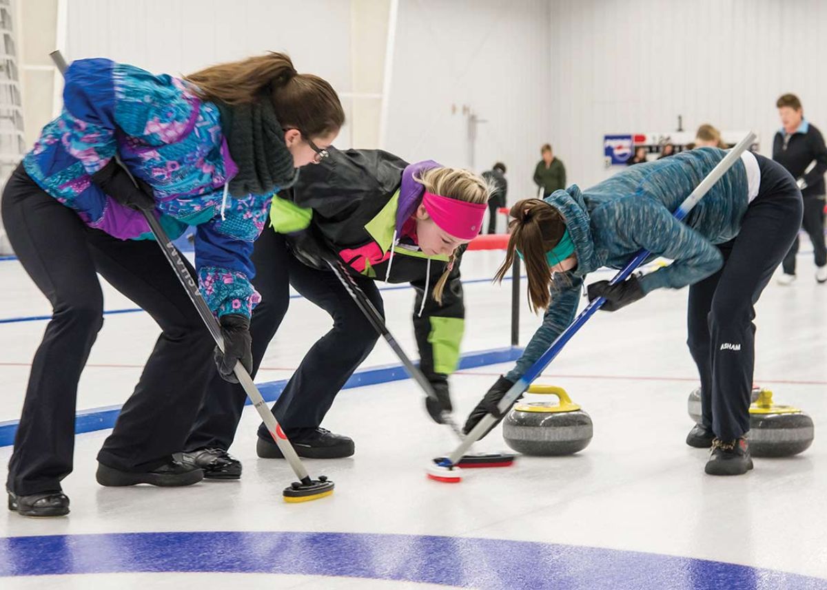 Three women sweeping the rock at the Lac du Bonnet Curling Rink