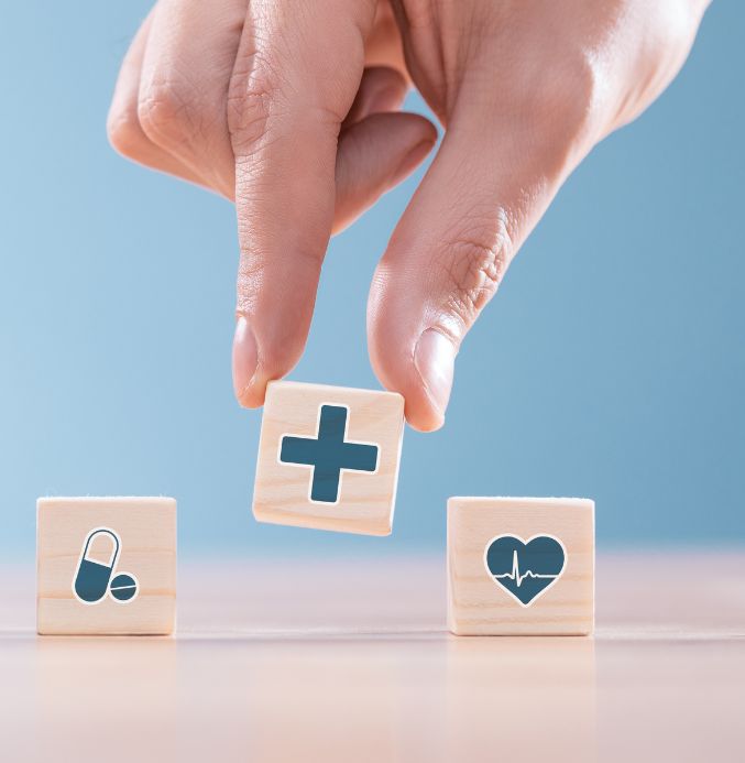 Close up of a hand placing blocks with medical symbols on a table depicting health and wellness in Lac du Bonnet