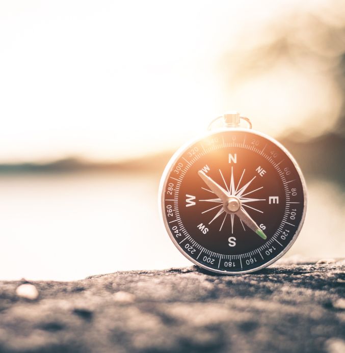 Image of a compass sitting on a rock depicting projects we are working on.