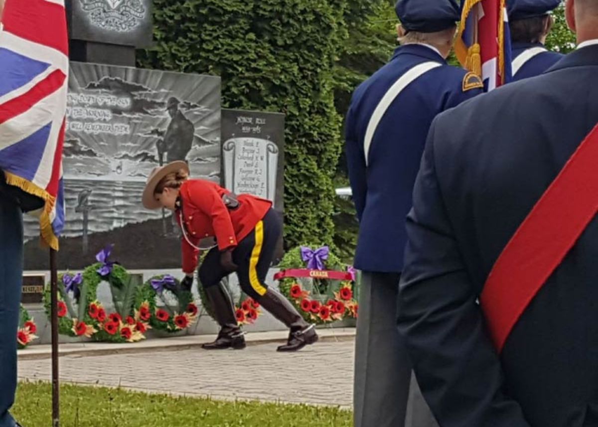 RCMP Officer placing a memorial wreath at a monument commemorating those lost in battle.