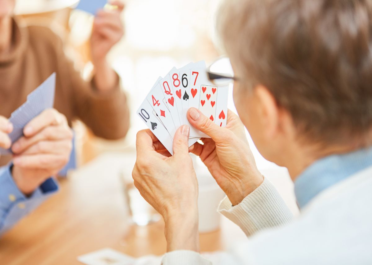 Close up of senior woman playing cards showing her hand to the camera