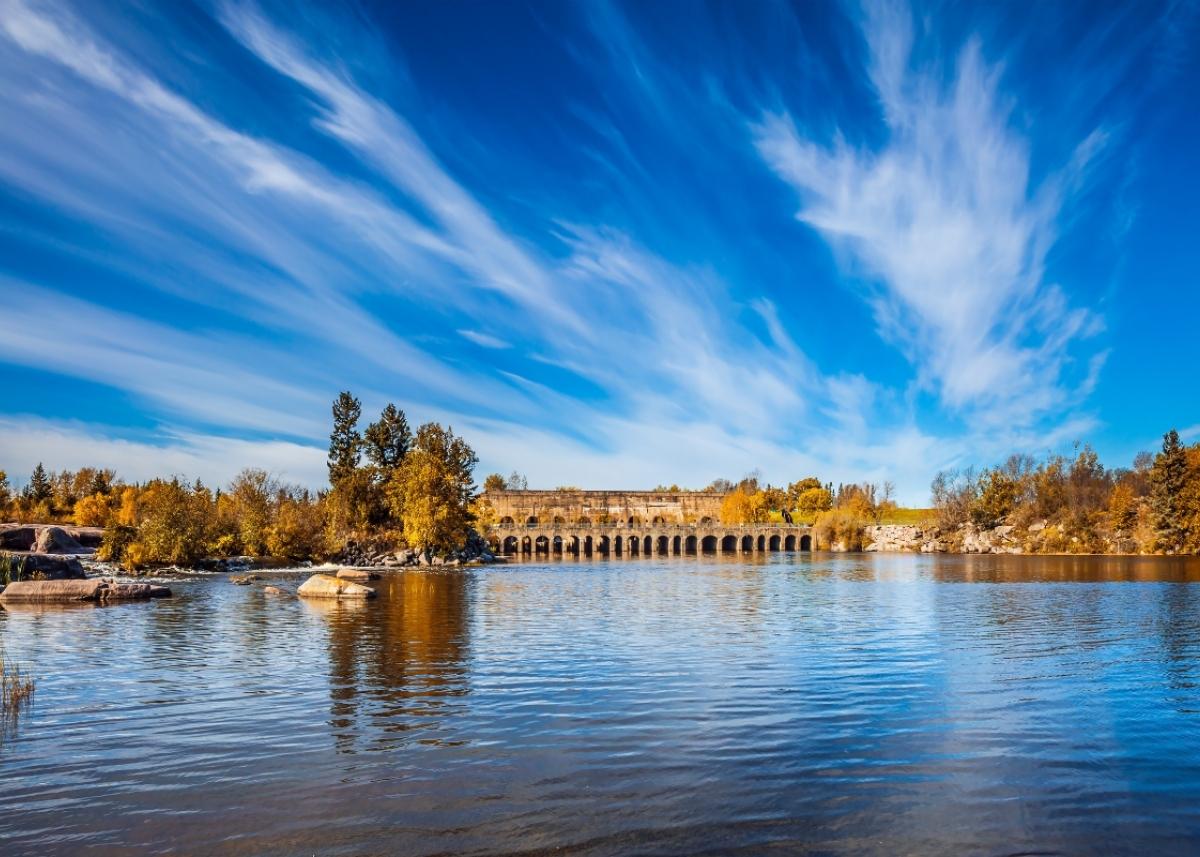 Photo of the Pinawa Dam Provincial Heritage Park along the water with a vibrant blue sky.