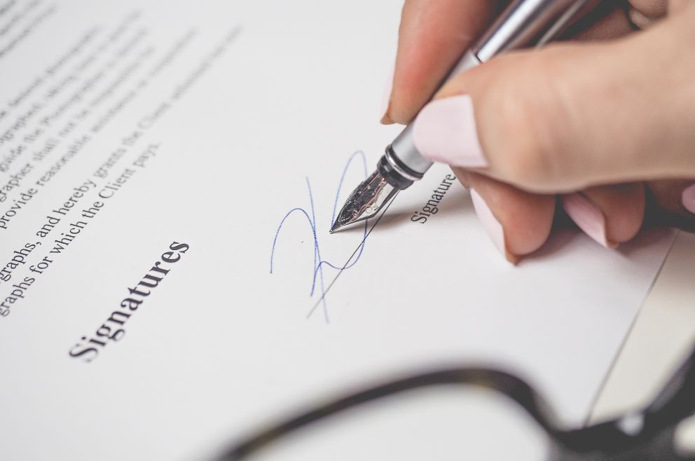 Close up of a woman's hand signing a contract depicting the Property Management Agreement.