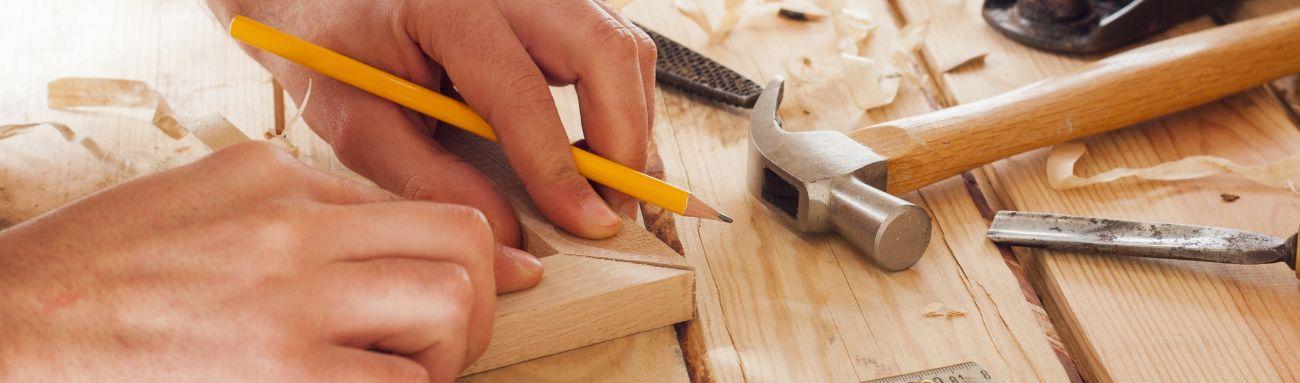 Photo showing a carpenter building something out of wood on a work table.